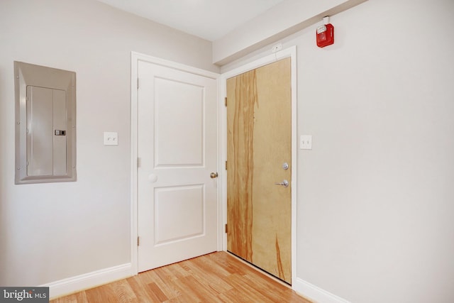 corridor with electric panel and light hardwood / wood-style floors