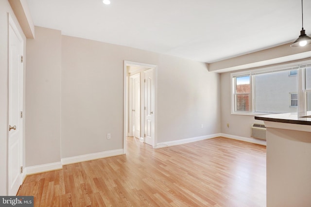 unfurnished living room with a wall unit AC and light wood-type flooring