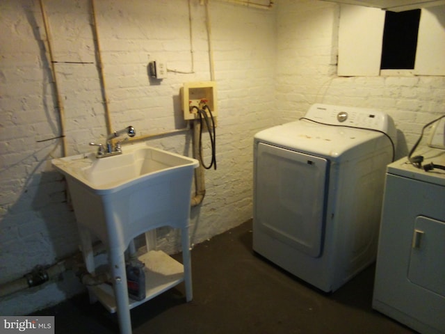 washroom featuring concrete block wall, laundry area, brick wall, and separate washer and dryer