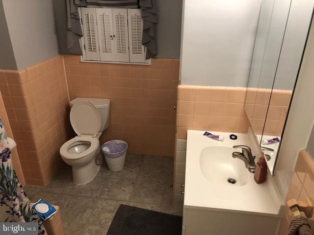 bathroom featuring tile patterned flooring, vanity, tile walls, and toilet