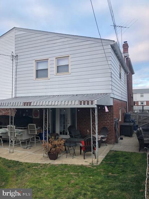 back of property featuring a lawn and a patio