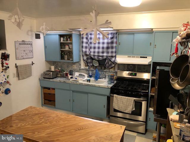 kitchen featuring decorative backsplash, stainless steel gas stove, blue cabinetry, and sink