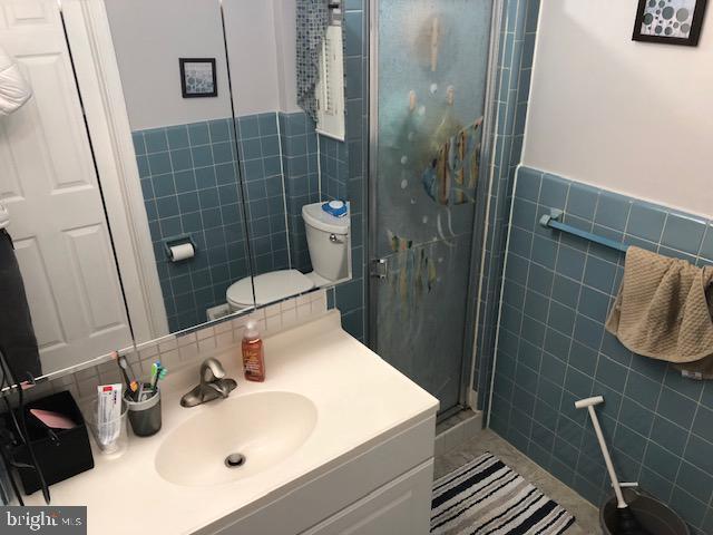 bathroom featuring vanity, a shower with door, and tile walls