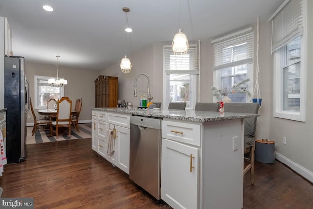 kitchen featuring white cabinetry, appliances with stainless steel finishes, an island with sink, and light stone counters