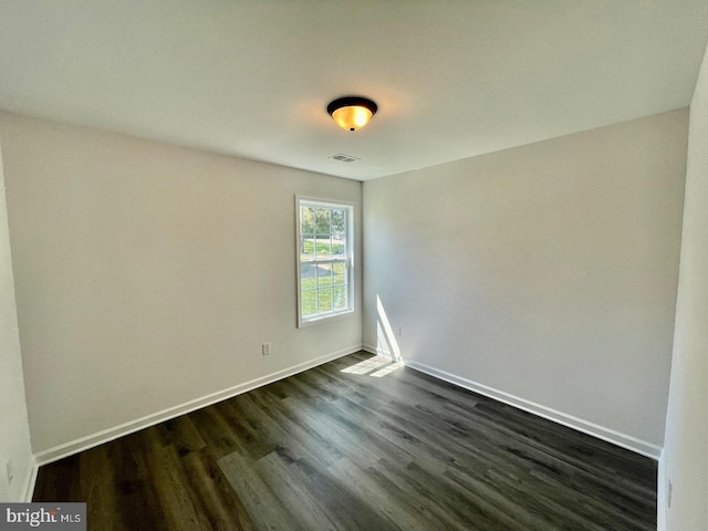 spare room featuring dark wood-style floors, baseboards, and visible vents