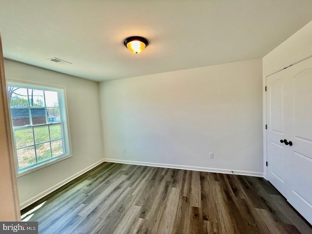 unfurnished bedroom featuring a closet, visible vents, dark wood finished floors, and baseboards