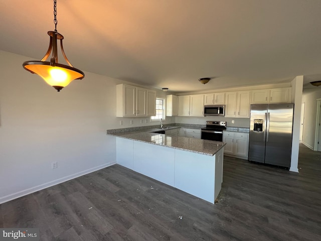 kitchen featuring white cabinets, appliances with stainless steel finishes, a peninsula, pendant lighting, and a sink