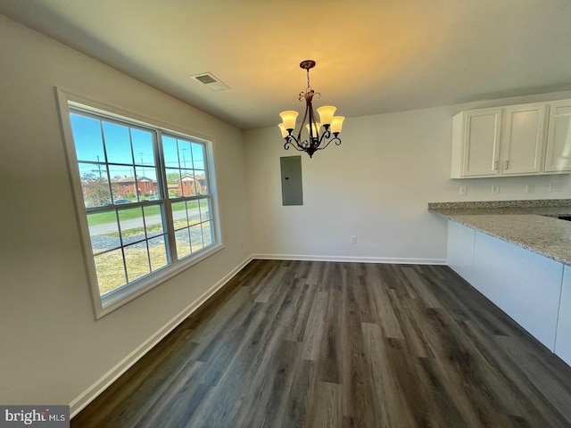 unfurnished dining area with dark wood-type flooring, electric panel, a notable chandelier, and baseboards