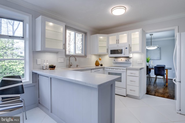 kitchen with sink, decorative light fixtures, kitchen peninsula, white appliances, and white cabinets