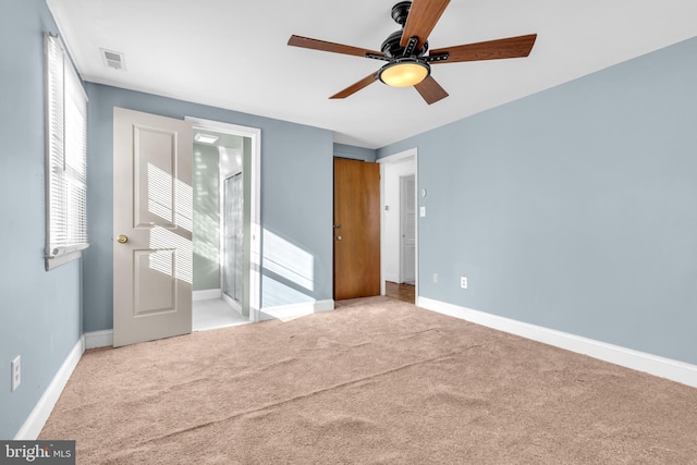 unfurnished bedroom with ceiling fan, a closet, light colored carpet, and ensuite bath