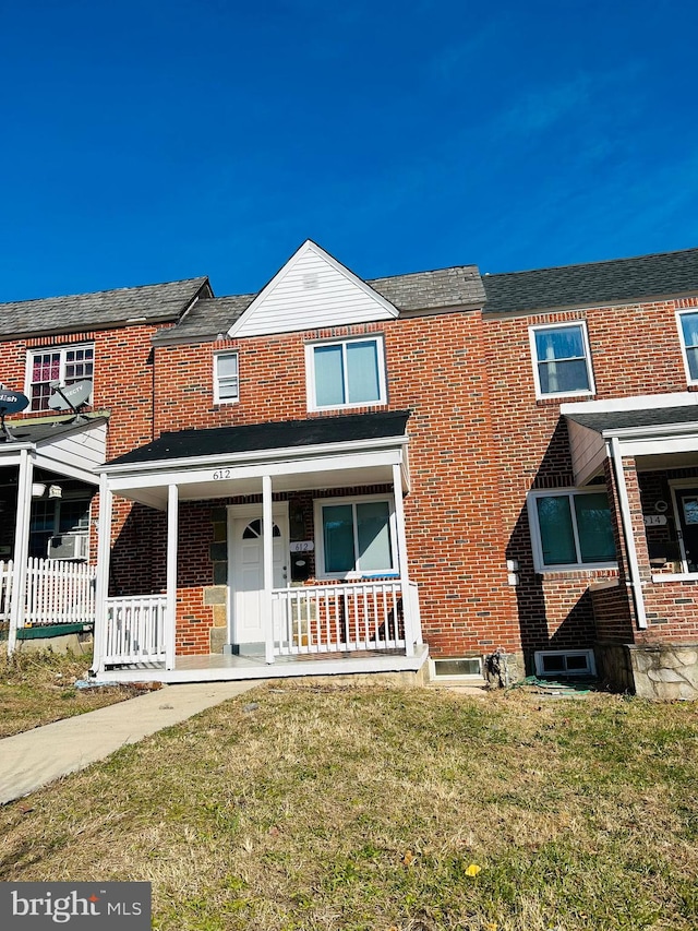 view of property featuring a porch and a front lawn