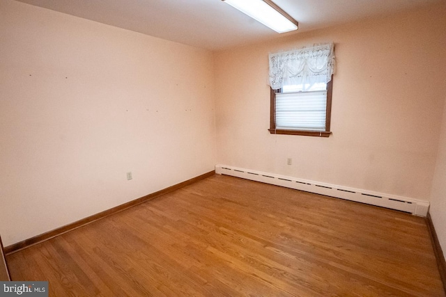 empty room with a baseboard radiator and hardwood / wood-style flooring