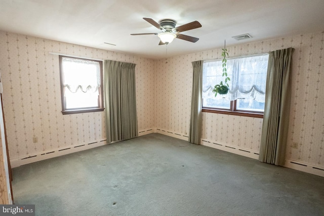 empty room featuring carpet floors, plenty of natural light, baseboard heating, and ceiling fan