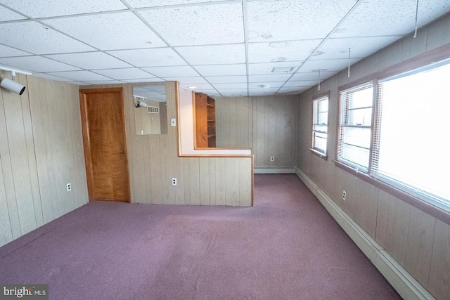 spare room with carpet, a paneled ceiling, and wood walls