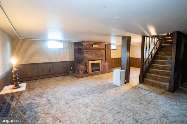 carpeted living room featuring wood walls and a brick fireplace