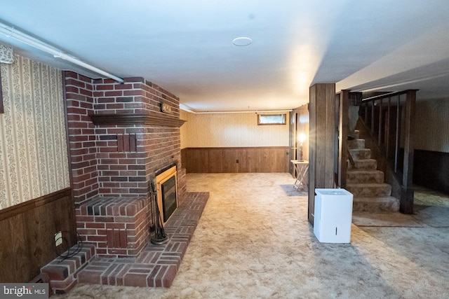 unfurnished living room featuring carpet flooring, wood walls, and a brick fireplace