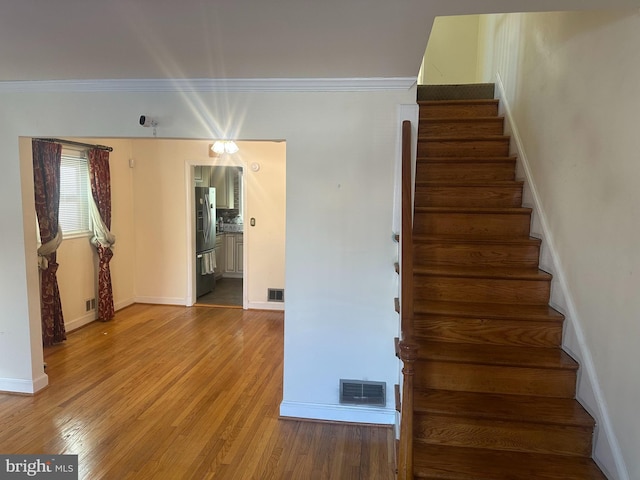 stairway featuring crown molding and wood-type flooring