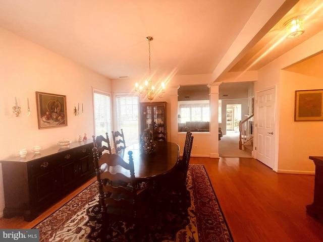 dining space with hardwood / wood-style flooring, decorative columns, and a chandelier