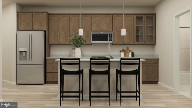 kitchen with a center island with sink, hanging light fixtures, white fridge with ice dispenser, light hardwood / wood-style floors, and a breakfast bar area