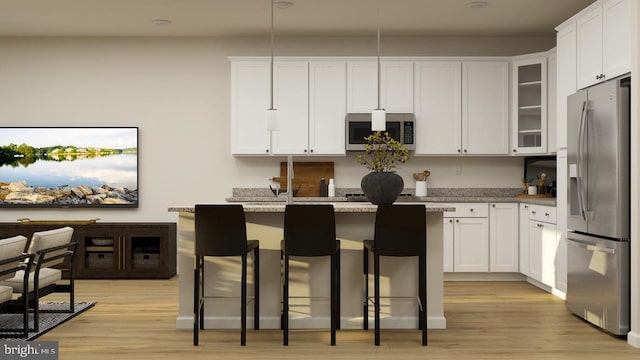 kitchen with a breakfast bar, appliances with stainless steel finishes, white cabinetry, and a kitchen island