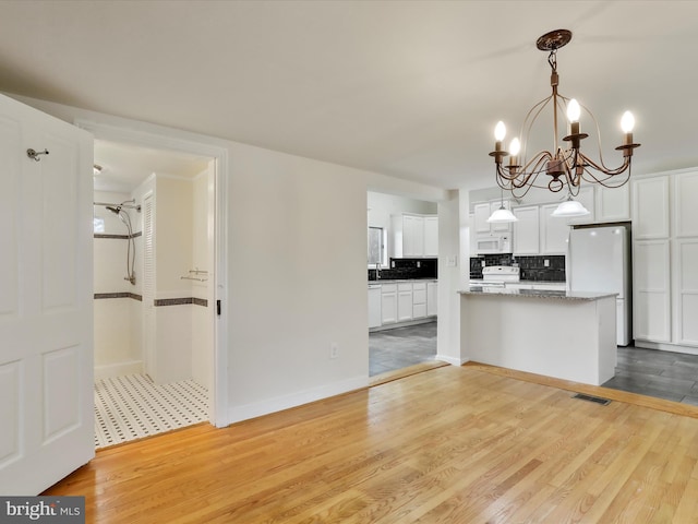 kitchen featuring white cabinetry, hardwood / wood-style floors, a chandelier, decorative light fixtures, and white appliances