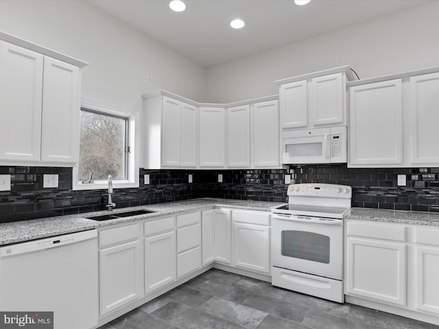 kitchen featuring white appliances, backsplash, sink, light stone countertops, and white cabinetry