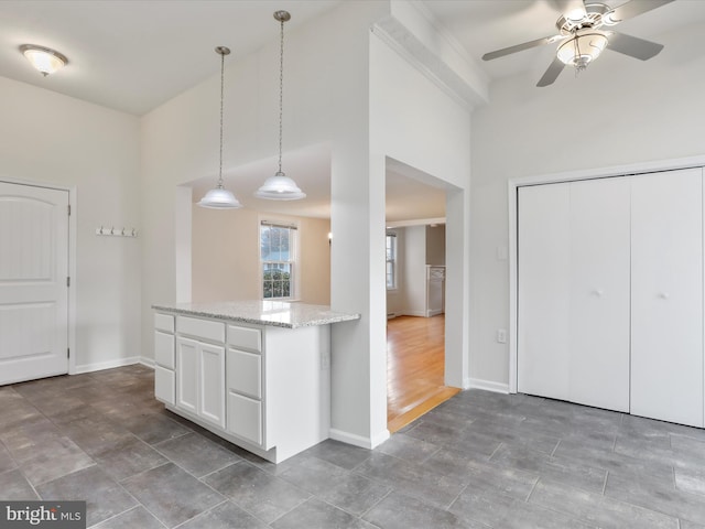 kitchen featuring white cabinets, ceiling fan, light stone countertops, and hanging light fixtures