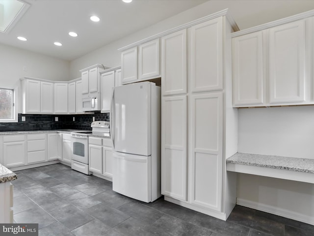 kitchen with light stone countertops, white appliances, and white cabinetry