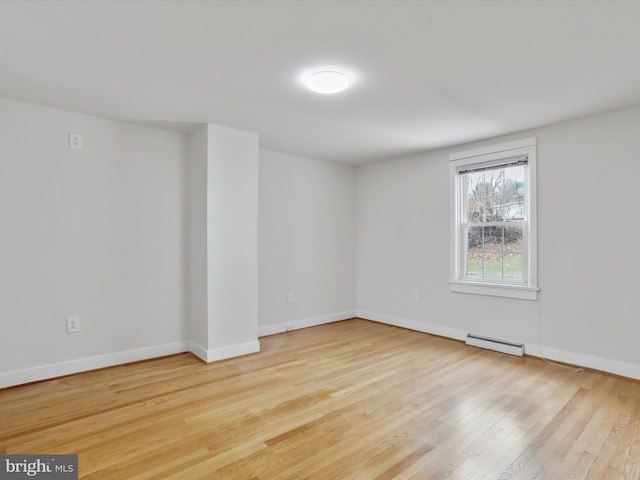 unfurnished room featuring a baseboard radiator and light hardwood / wood-style floors