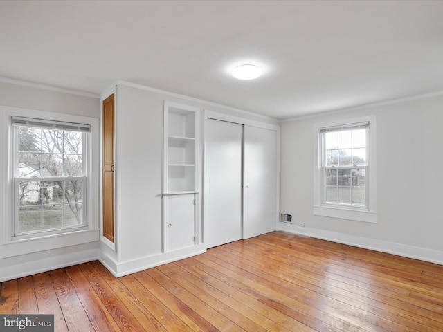 unfurnished bedroom featuring light wood-type flooring and crown molding