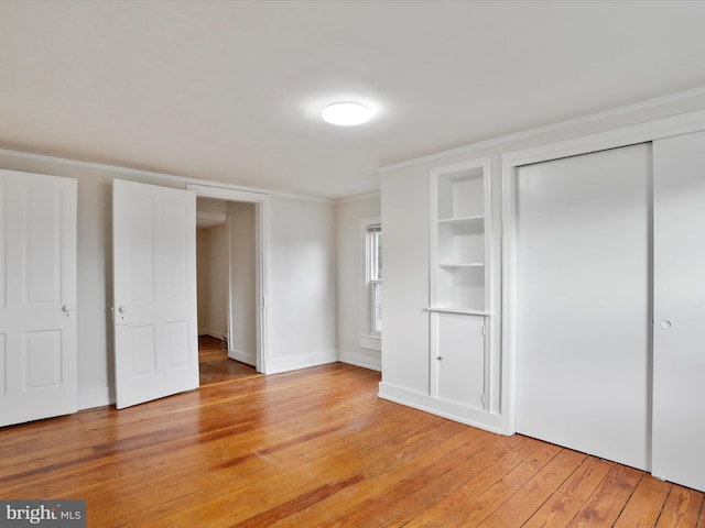 unfurnished bedroom with light wood-type flooring, a closet, and crown molding