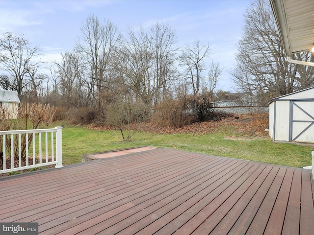 wooden terrace with a storage unit and a lawn