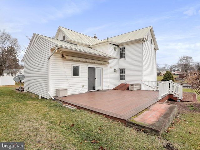 rear view of house featuring a wooden deck and a yard