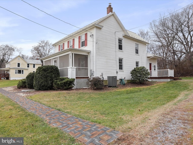 view of home's exterior featuring a lawn, a sunroom, and central AC