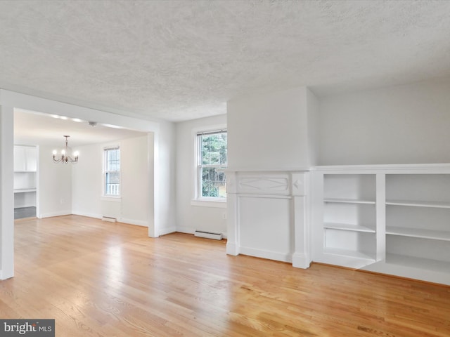 spare room with light hardwood / wood-style floors, built in features, a baseboard radiator, and an inviting chandelier