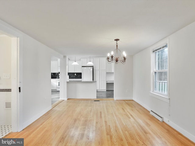 unfurnished living room featuring a baseboard heating unit, light hardwood / wood-style flooring, and an inviting chandelier