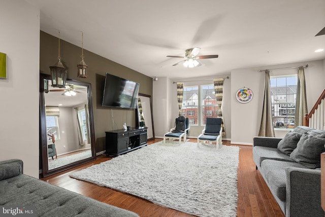 living room featuring ceiling fan, plenty of natural light, and dark wood-type flooring