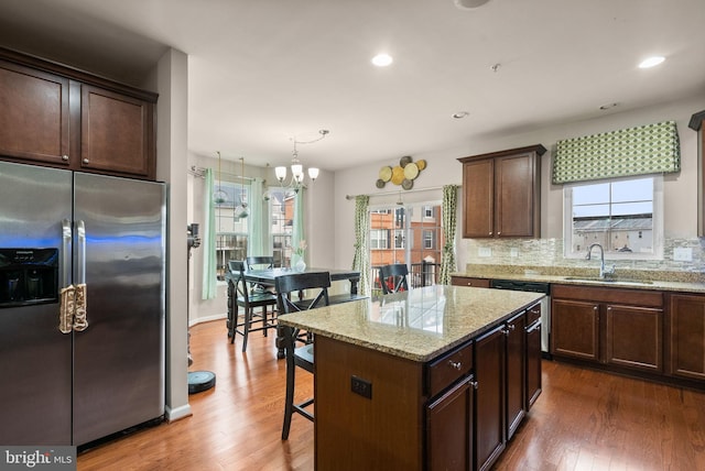 kitchen with appliances with stainless steel finishes, sink, pendant lighting, a notable chandelier, and a center island