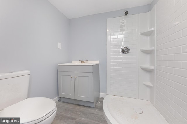 bathroom with hardwood / wood-style floors, vanity, toilet, and a shower