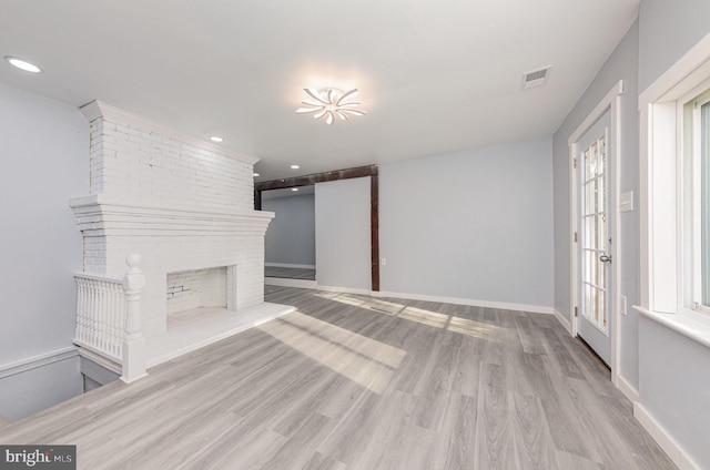 unfurnished living room with light hardwood / wood-style floors and a brick fireplace