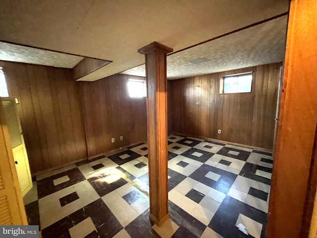 basement with a textured ceiling and wood walls