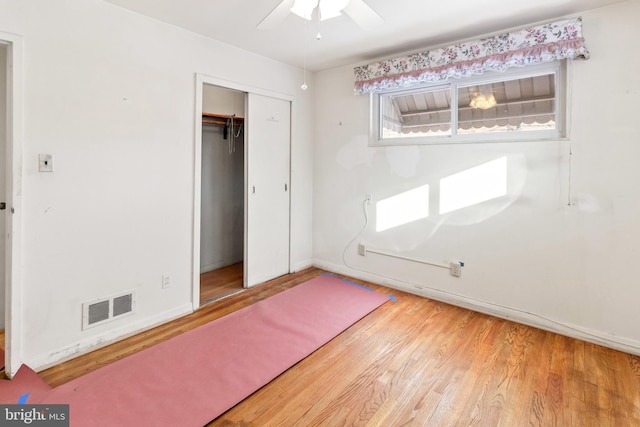 unfurnished bedroom featuring hardwood / wood-style floors, a closet, and ceiling fan