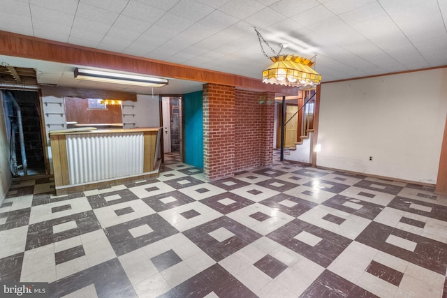 interior space with ornamental molding and brick wall