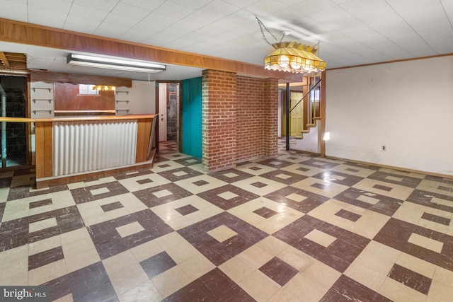 basement with crown molding, brick wall, and indoor bar