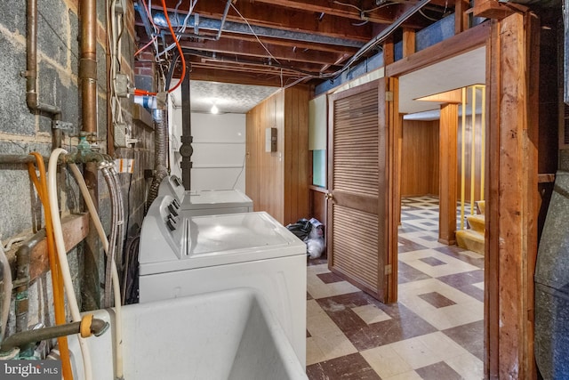 clothes washing area featuring washer and dryer and wood walls