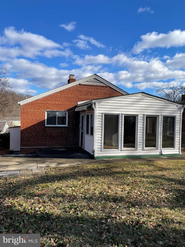 rear view of house featuring a lawn and a patio