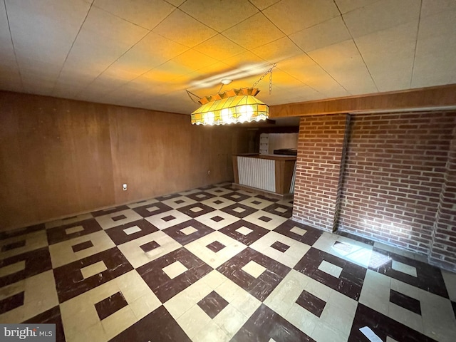 unfurnished dining area featuring brick wall and wooden walls