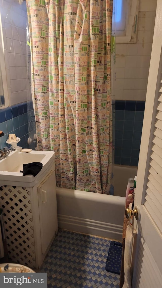 bathroom featuring backsplash, shower / tub combo with curtain, tile walls, and sink