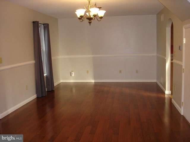 empty room with dark hardwood / wood-style floors and an inviting chandelier