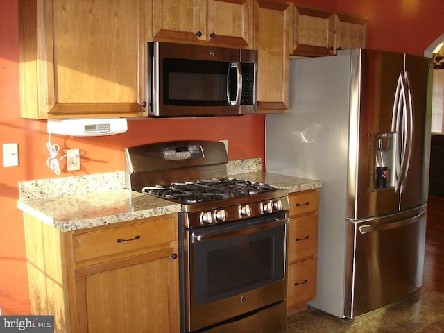 kitchen with light stone countertops, dark tile patterned floors, and stainless steel appliances